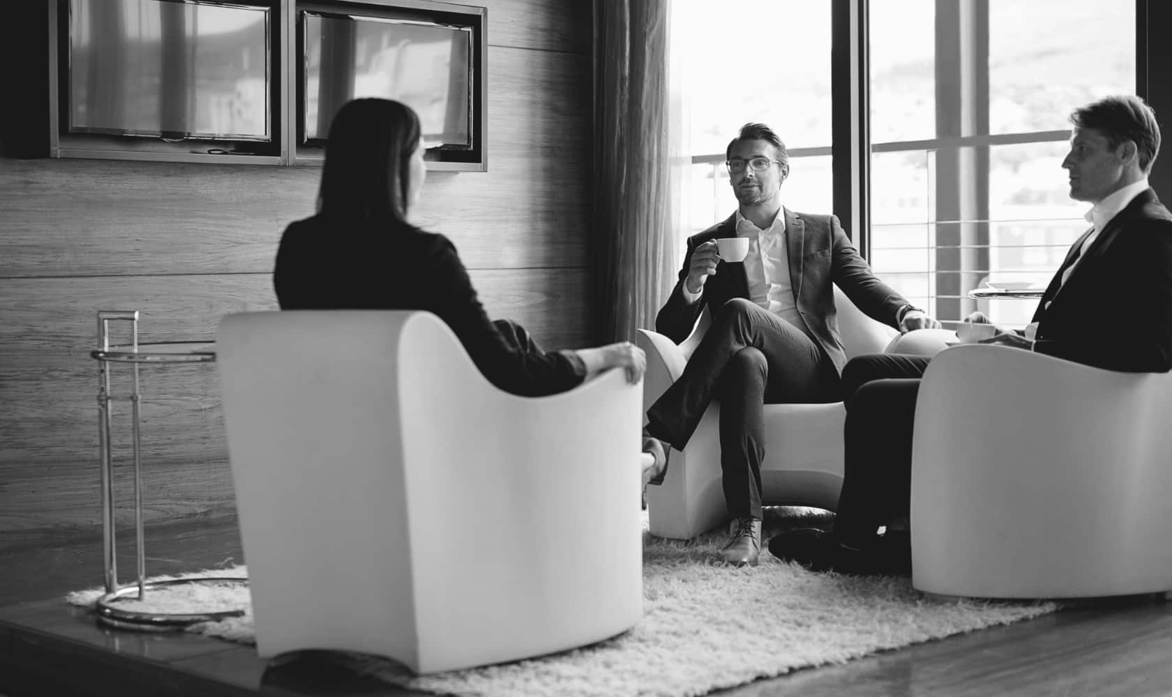 Three professionals sitting in chairs holding white mugs